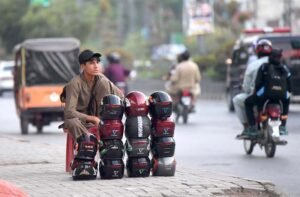Street Vendor Sells Safety Helmets Amid Traffic Concerns on Murree Road